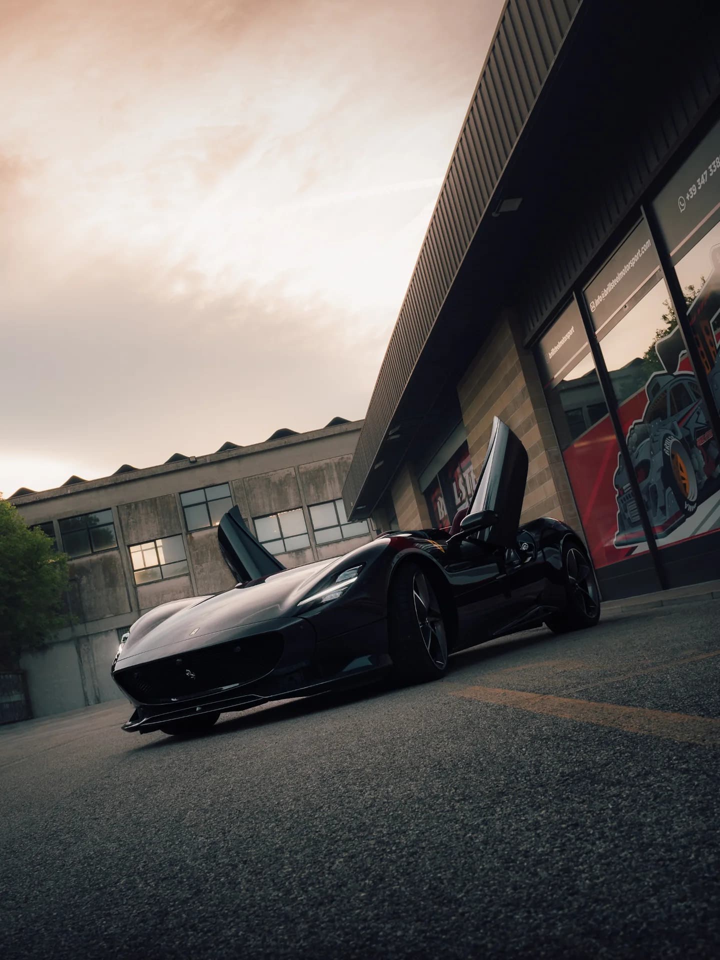 Ferrari Monza SP2 with butterfly doors raised at sunset in front of Brill-Steel workshop